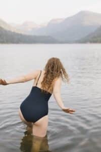 woman in a black bathing suit going for a swim in a lake in canada
