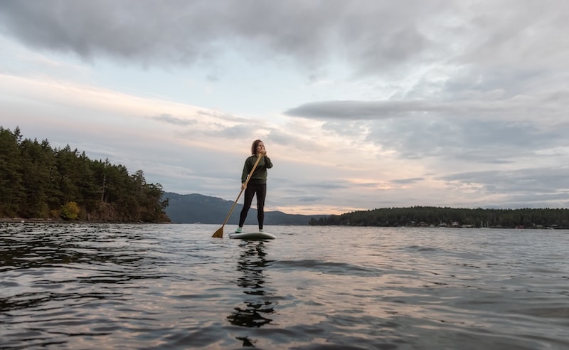 woman paddleboarding on a peaceful lake in the summer