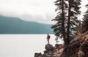 hiker on a rocky outcropping over a lake - hiking by a lake 