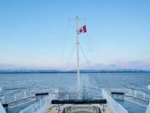 bright blue sky in front of a ferry off the coast of Vancouver Island flying a Canadian Flag