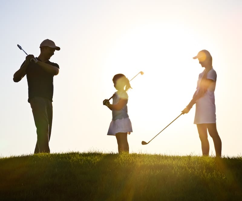 Family of a golfers playing golf at sunset