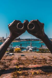 bronze statue of hands holding binoculars in Victoria's Inner Harbour walkway