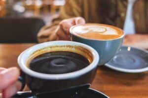 Closeup image of a couple people clinking coffee cups together in cafe