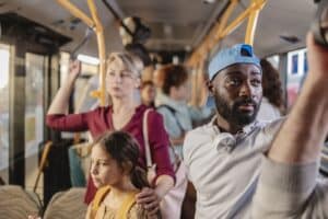 Diverse group of people standing and holding on to handrails inside a crowded public transport bus, commuting through the city during rush hour