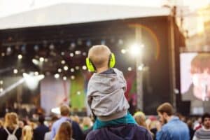 Boy with headphones being carried on shoulders during festival
