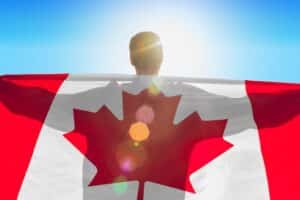 Man with a flag of Canada standing in morning field