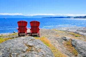 two red chairs side-by-side on the rocks above the ocen - ocean view in the summer in Victoria