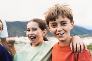 Group of kid friends having fun outside - Latin children celebrating and hugging together - Childhood friendship and life style concept