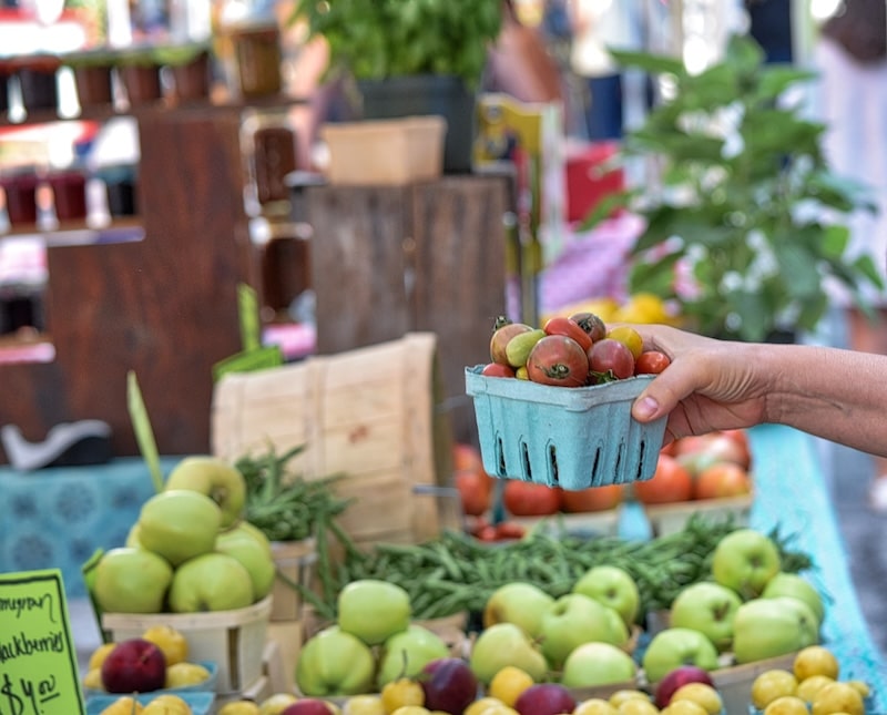 hand of an unrecognizable woman choosing fruit from a farmers market