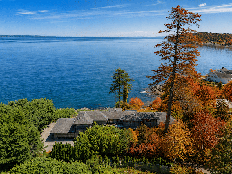 aerial photo of a large oceanfront home on Vancouver Island with the surrounding foliage transitioning from summer to fall