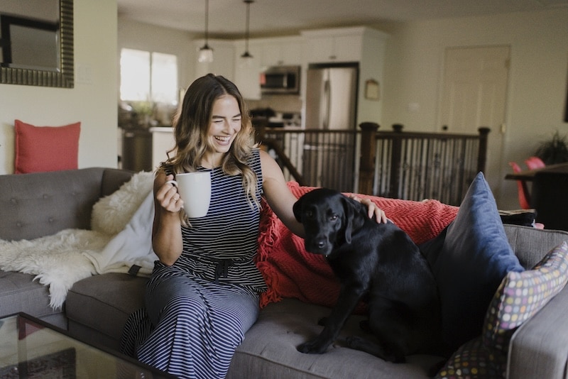 Woman enjoying a cozy moment with her black dog on the couch